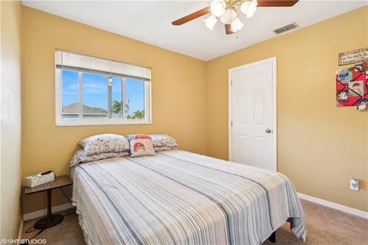 Carpeted bedroom with a ceiling fan, baseboards, and visible vents