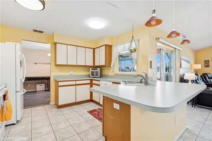Kitchen featuring visible vents, open floor plan, light countertops, white appliances, and a sink