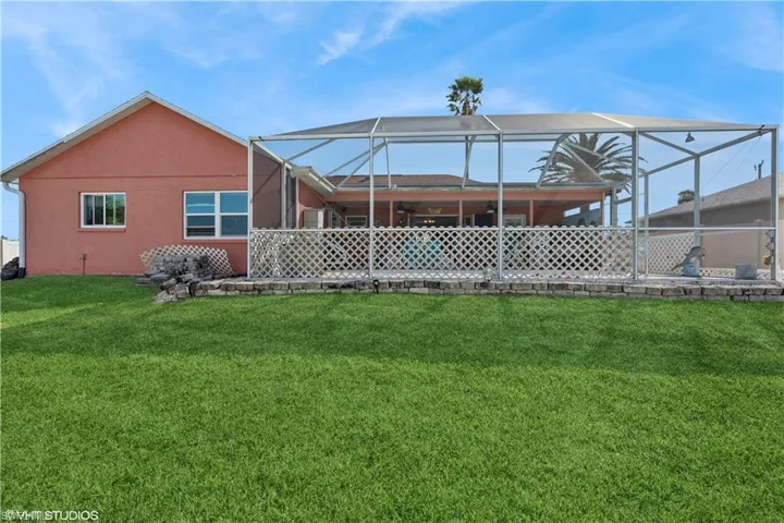 Rear view of property with a lanai, a yard, and stucco siding