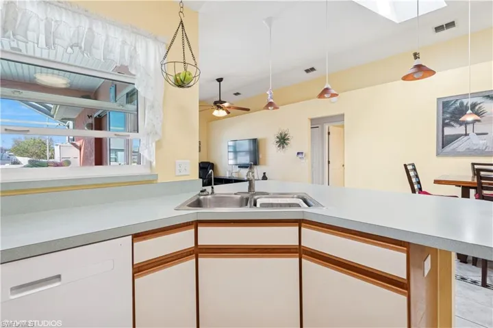 Kitchen featuring visible vents, dishwasher, pendant lighting, light countertops, and a sink