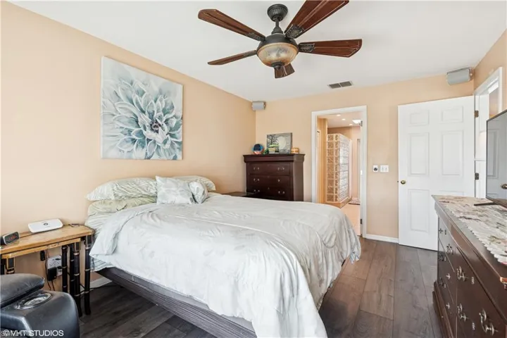 Bedroom featuring a ceiling fan, baseboards,  and dark wood-style flooring