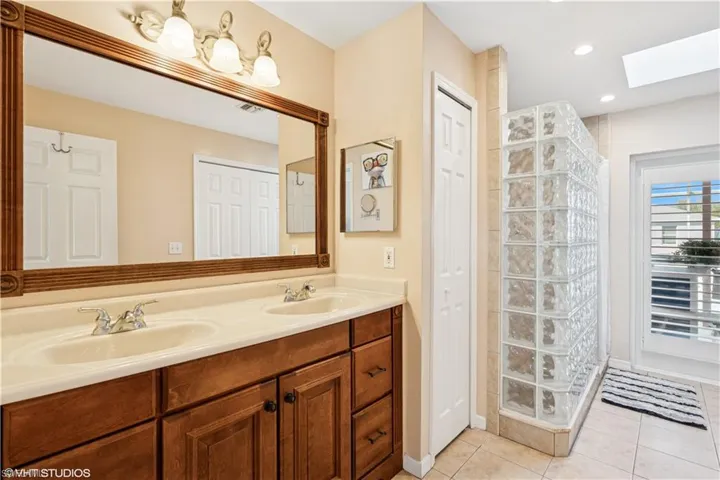 Full bathroom with tile patterned flooring, double vanity, a skylight, and a sink