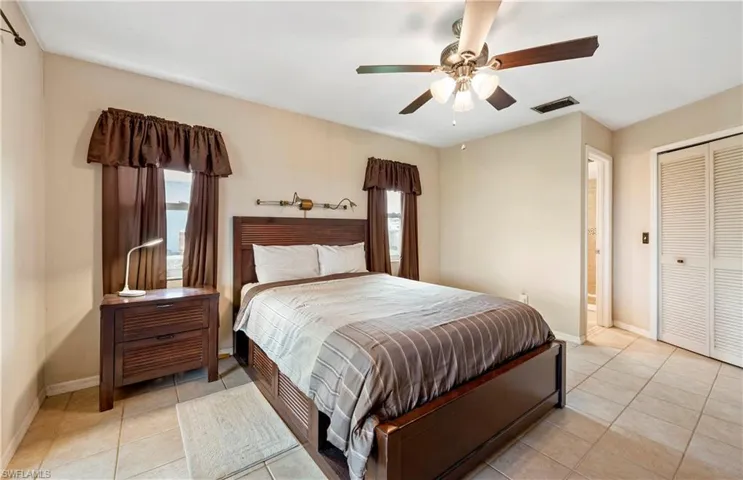 Bedroom with baseboards, light tile patterned floors, a ceiling fan, and a closet