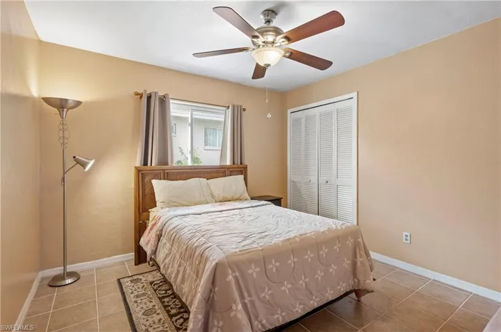 Bedroom with a closet, light tile patterned flooring, baseboards, and ceiling fan