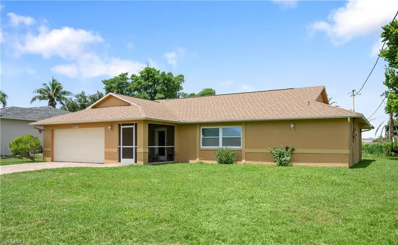 Ranch-style house featuring stucco siding, driveway, brick siding, and a front lawn