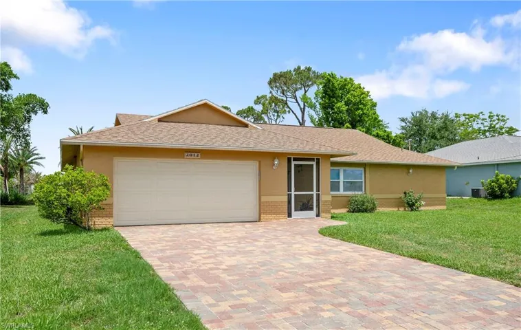 Ranch-style house featuring brick siding, a garage, a front lawn, decorative driveway, and stucco siding