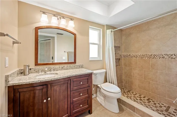 Full bath featuring toilet, vanity, a tile shower, and tile patterned floors