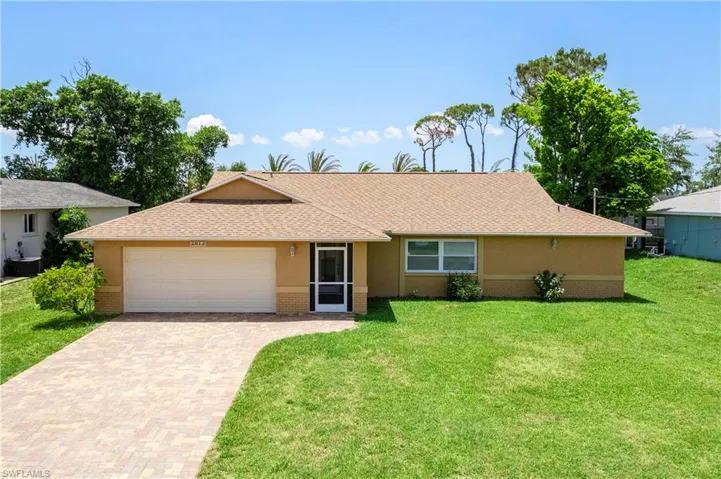Single story home featuring a garage, a front yard, decorative driveway, and stucco siding
