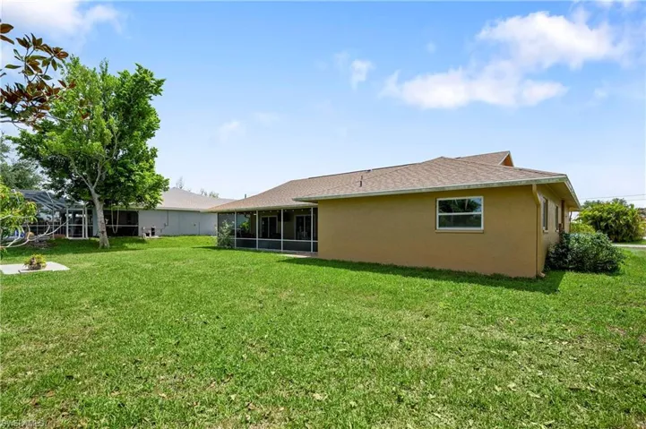 Back of house featuring a lawn, stucco siding, a sunroom, and a shingled roof
