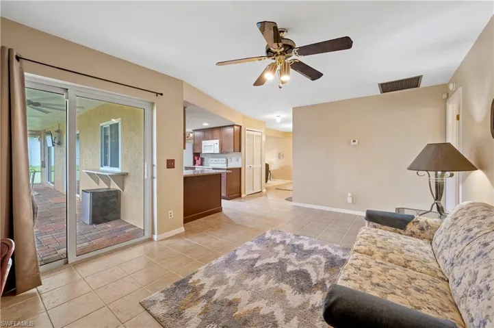 Living area with light tile patterned floors, a ceiling fan, and baseboards