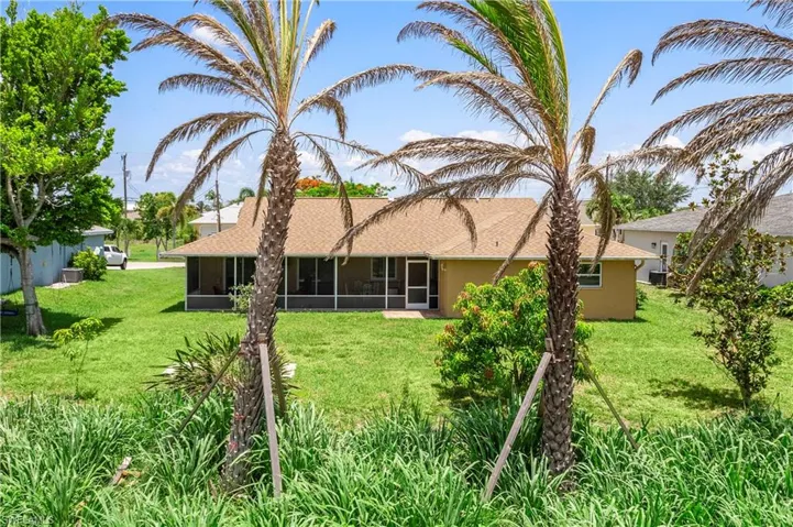 Back of property with a sunroom, stucco siding, and a lawn