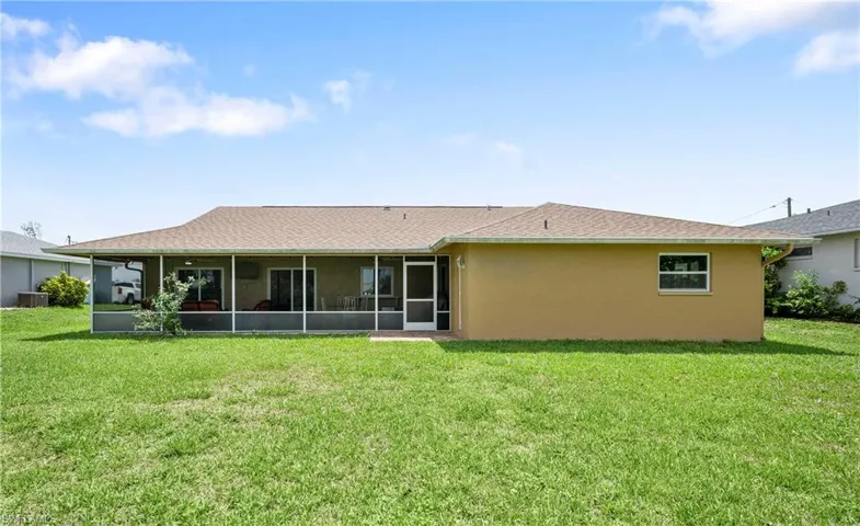Rear view of house featuring a sunroom, a yard, stucco siding, and central AC