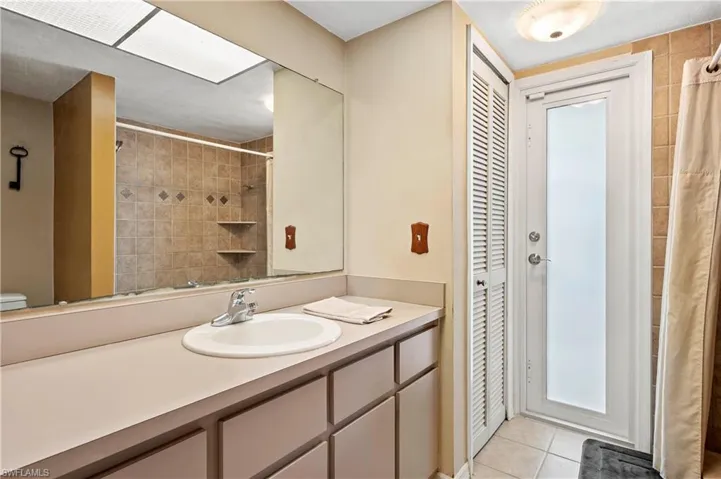 Bathroom with a closet, vanity, tile patterned flooring, a shower with shower curtain, and toilet