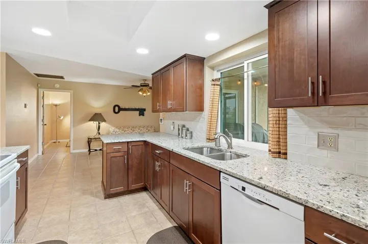 Kitchen with dishwasher, a sink, decorative backsplash, a peninsula, and baseboards