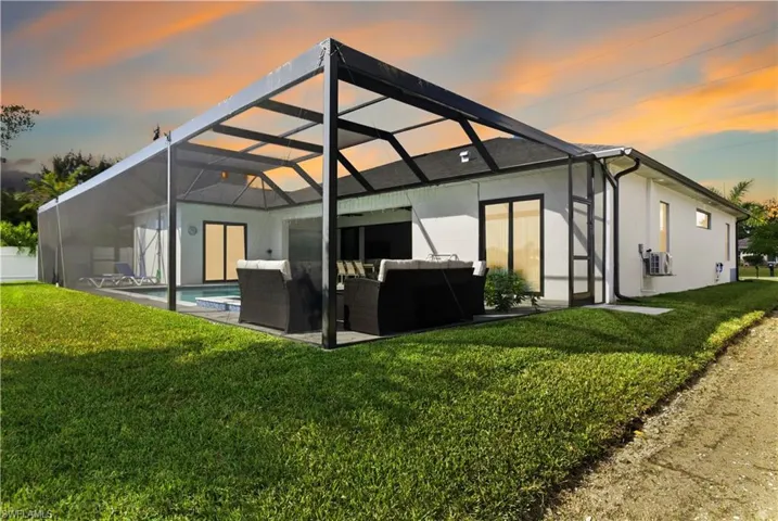 Rear view of house with a lanai, an outdoor living space, a lawn, a sunroom, and stucco siding