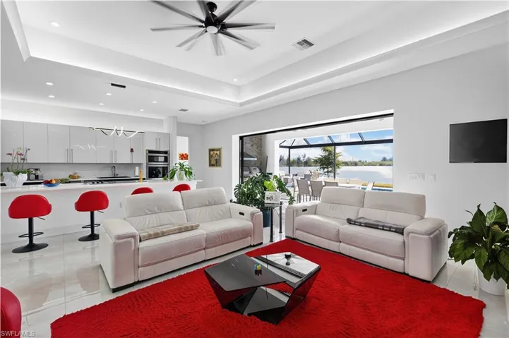 Living room with a raised ceiling, ceiling fan, and recessed lighting