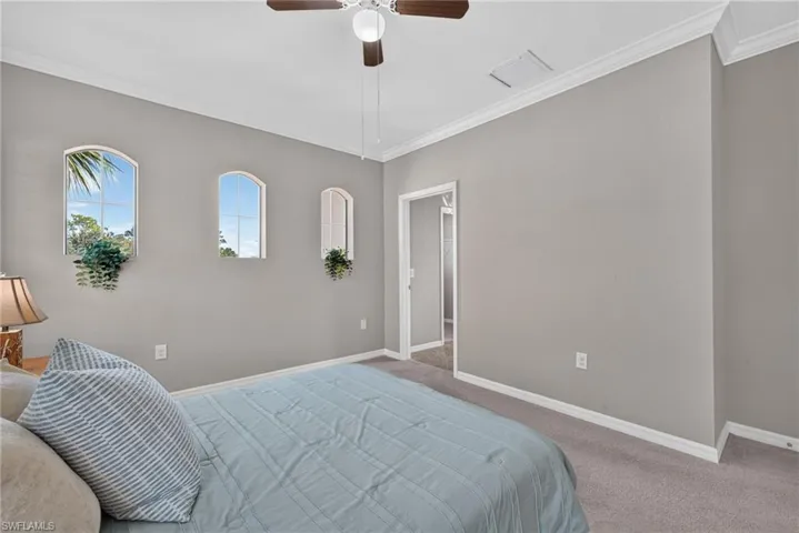 rimary bedroom with crown molding and ceiling fan with ensuite bathroom and large walk-in closet