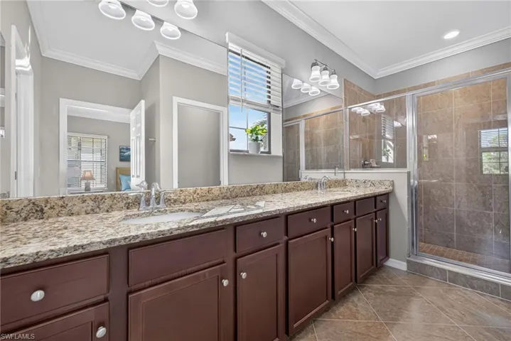 Primary ensuite bathroom with double vanity, granite countertops, shower, and large walk-in closet.