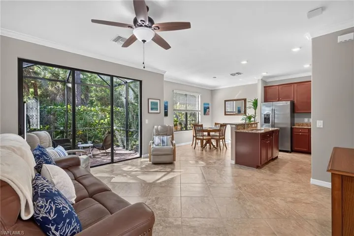 Spacious, open living area with crown molding, ceiling fan, and access to large kitchen and screened patio/lanai