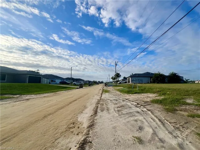 View of dirt / gravel road featuring a residential view and street lights