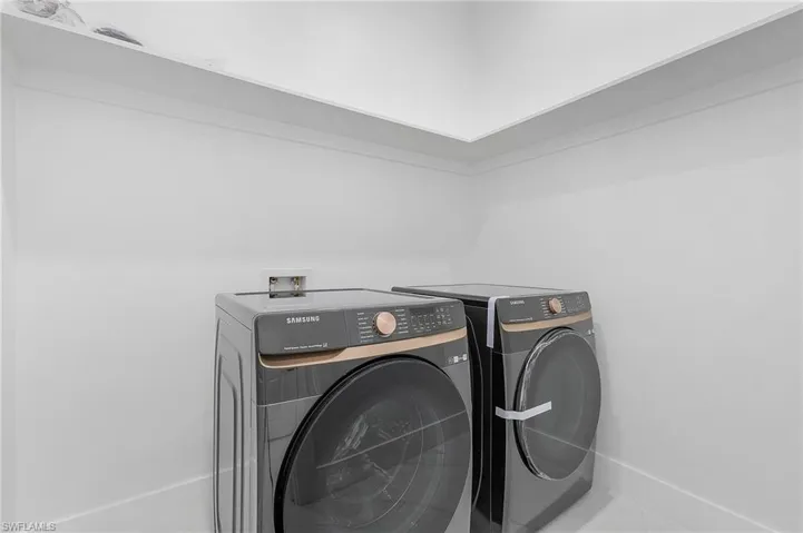 Washroom featuring tile patterned flooring and washing machine and dryer