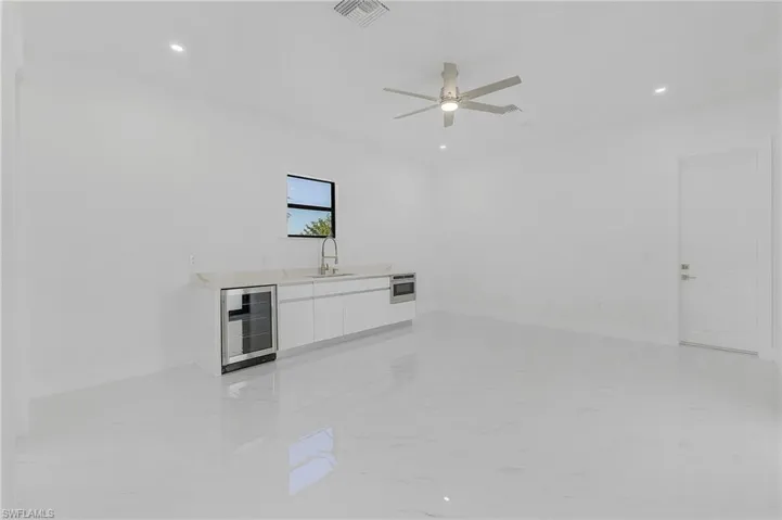 Unfurnished living room with ceiling fan, sink, and beverage cooler