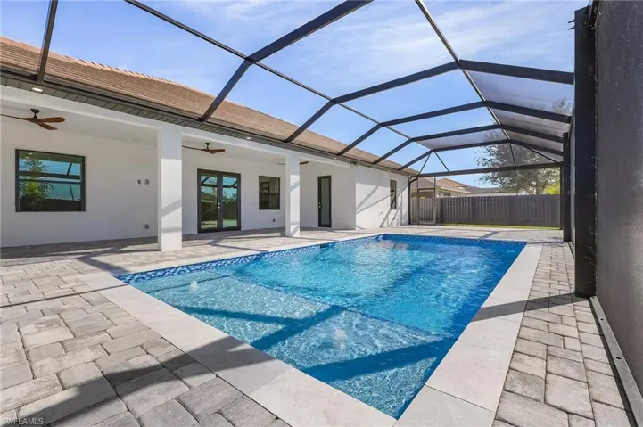 View of swimming pool featuring ceiling fan, a patio area, and glass enclosure