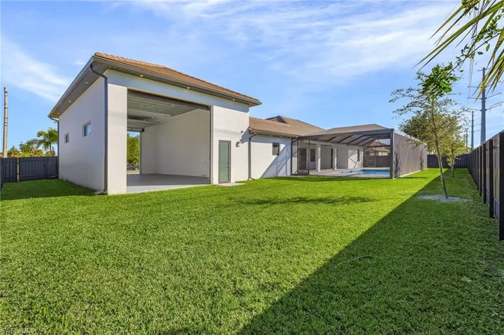 Back of house featuring a fenced in pool, glass enclosure, a patio area, and a lawn
