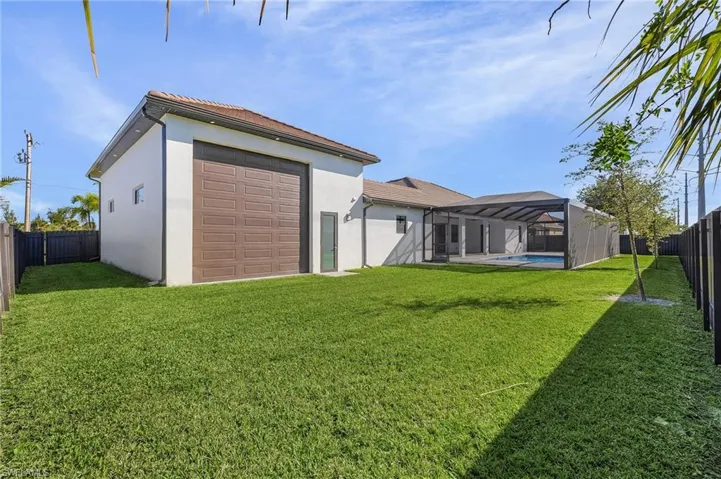 Rear view of property featuring a lanai, a fenced in pool, and a lawn