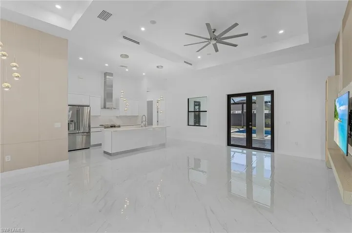 Living room with french doors, ceiling fan, a raised ceiling, and sink