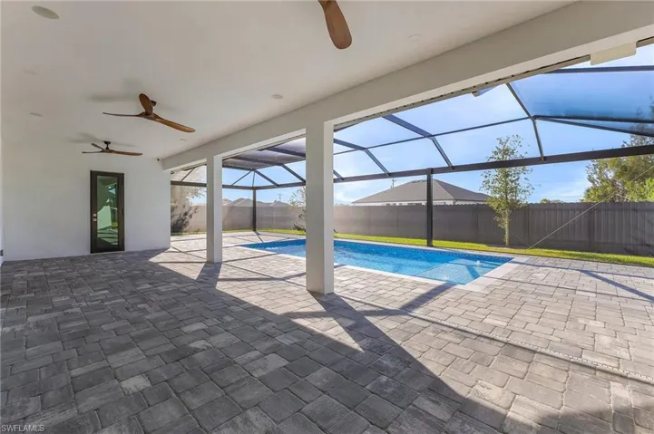 View of swimming pool featuring a lanai, ceiling fan, and a patio