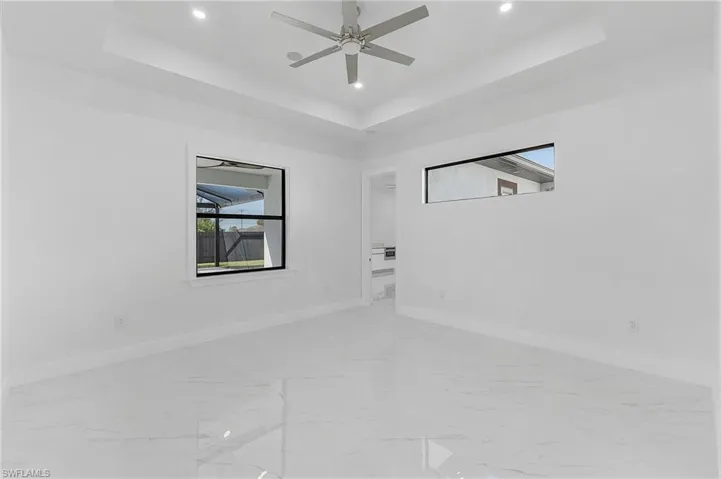 Empty room with ceiling fan and a tray ceiling