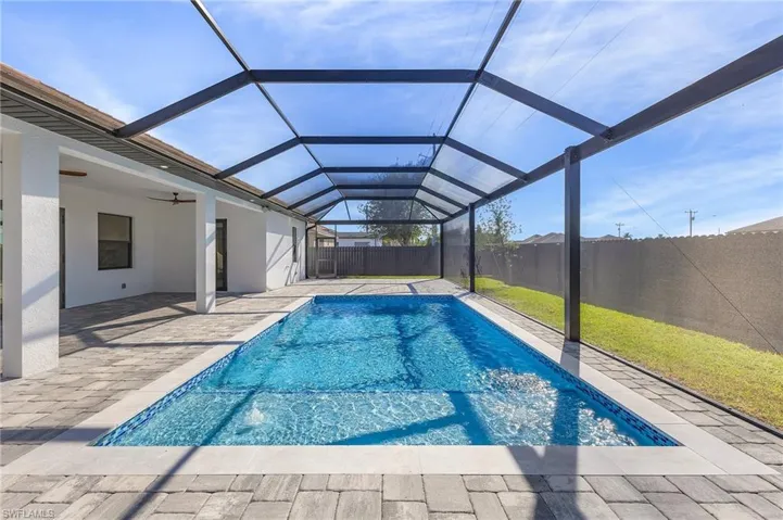 View of swimming pool with ceiling fan, glass enclosure, and a patio area