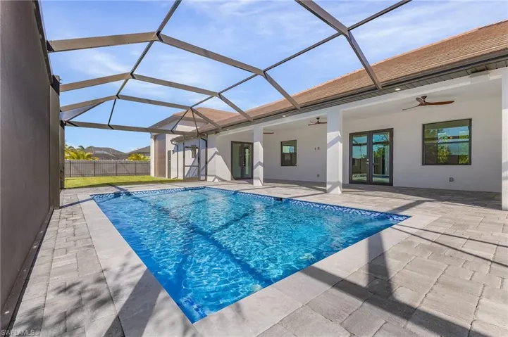 View of swimming pool with ceiling fan, glass enclosure, and a patio