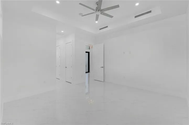 Unfurnished room with ceiling fan and a tray ceiling