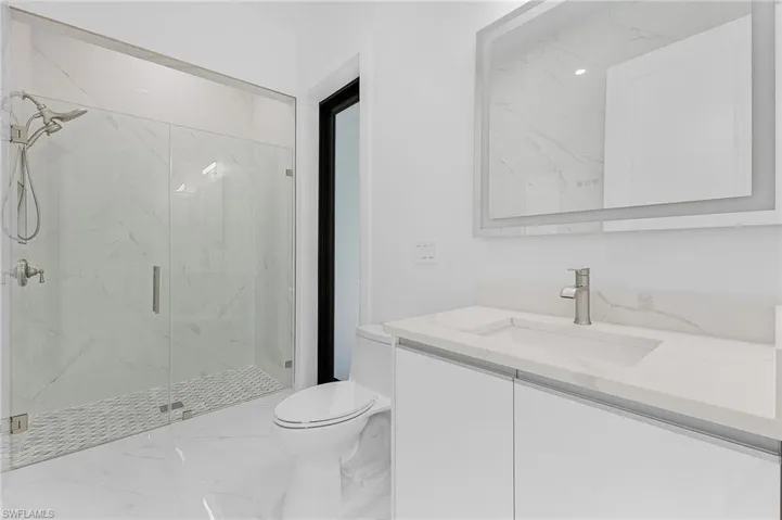 Bathroom with toilet, vanity, and a shower with door