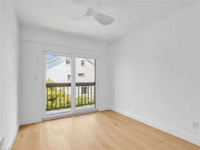 Light wood-finish flooring, white walls, and a modern ceiling fan