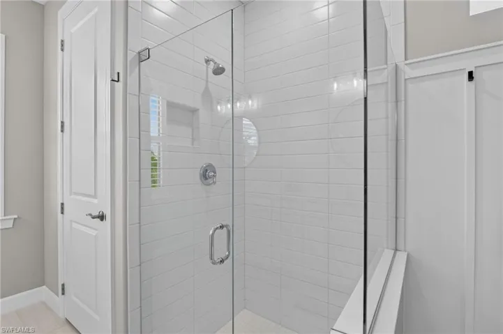 Glass-enclosed shower featuring white subway tile, a built-in shower niche, and a chrome showerhead