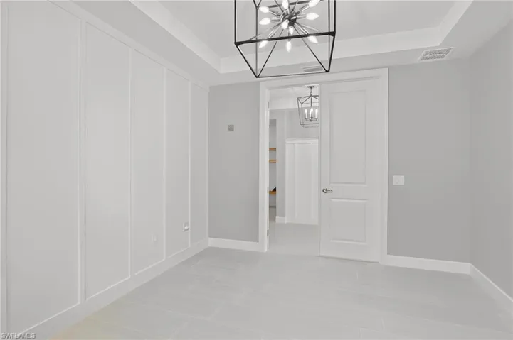 Interior space featuring plank wall paneling, a tray ceiling, and a modern geometric chandelier