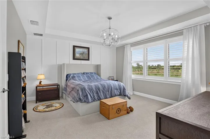 Spacious bedroom featuring a tray ceiling, recessed lighting, and a contemporary chandelier