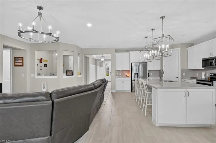 Open-concept living area featuring light wood-finish flooring, recessed lighting, and a contemporary chandelier