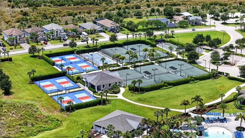 Recreational area featuring multiple sports courts, including blue and orange pickleball courts and green tennis courts, surrounded by manicured lawns and tropical landscaping