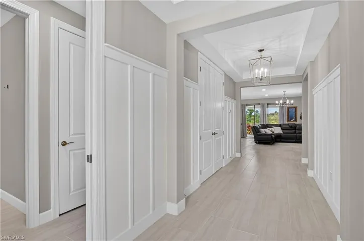 Hallway with light-toned tile flooring and tray ceiling