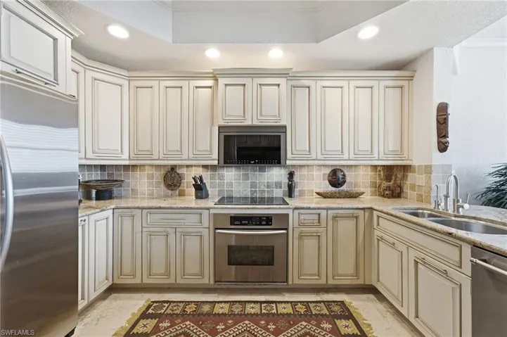 The kitchen is further enhanced by elegant recessed lighting and a sophisticated tray ceiling, adding architectural depth and a warm, inviting ambiance to this beautifully designed culinary space.