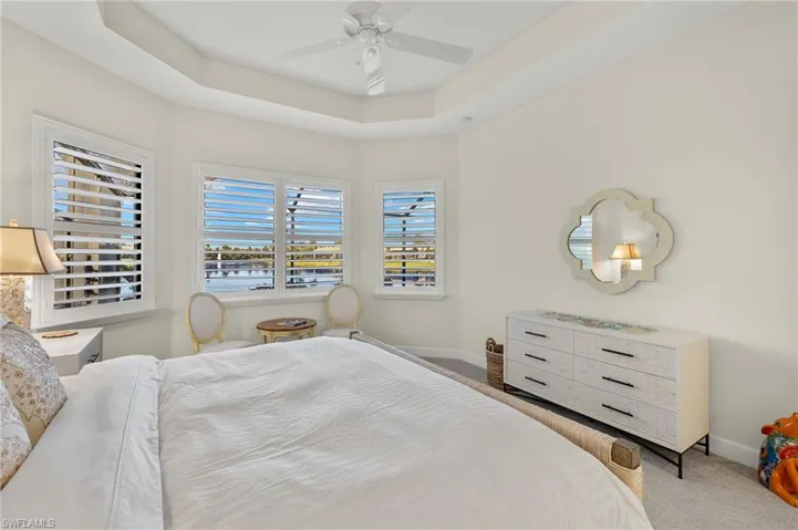 Carpeted bedroom featuring a raised ceiling and ceiling fan