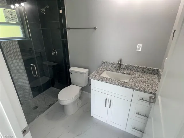 Bathroom with vanity, a stall shower, and light marble finish floors