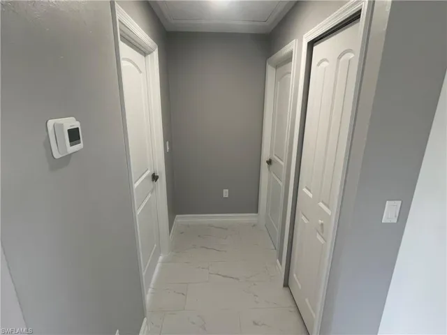 Hallway with light marble finish floors and baseboards