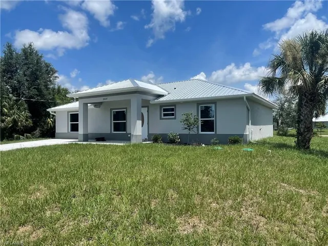 Rear view of property with stucco siding, a yard, and a metal roof