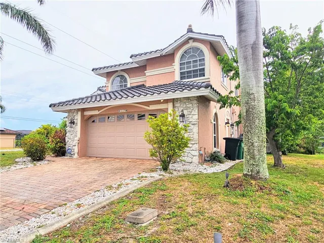 View of front of property with stone siding, decorative driveway, a tile roof, stucco siding, and a garage