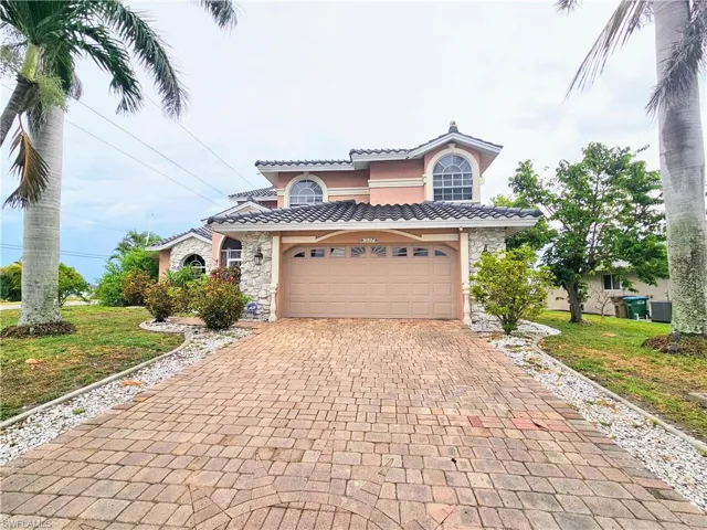 Mediterranean / spanish home featuring stone siding, decorative driveway, a tile roof, and a garage